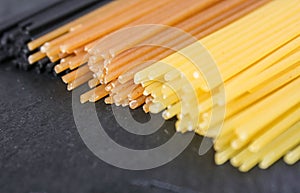 Spaghetti in three colors on a black basalt background