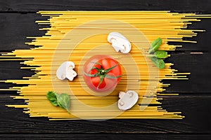 Spaghetti with tomato, mushrooms and spinach on black background. Top view. Healthy eating concept. Preparation of