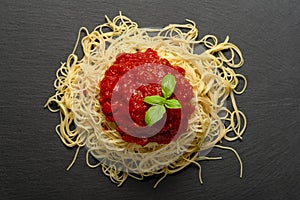Spaghetti with tomato sauce on a black granite plate. Cooked spaghetti with red sauce