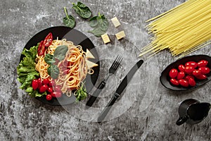 Spaghetti with tomato sauce, cherry tomatoes and basil on a dark background. Tasty appetizing classic italian spaghetti pasta with