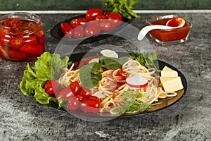 Spaghetti with tomato sauce, cherry tomatoes and basil on a dark background. Tasty appetizing classic italian spaghetti pasta with