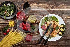 Spaghetti with tomato sauce, cherry tomatoes and basil on a dark background. Tasty appetizing classic italian spaghetti pasta with