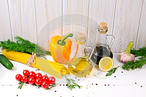 Spaghetti, tomatoes cherry, olive oil, herb and spices on old white wooden background. Set for healthy foods. Ingredients for sala