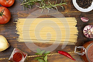 Spaghetti, tomatoes, garlic, peppers and herbs over wood table