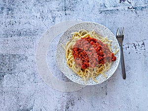 Spaghetti with tuna sauce on rustic grey background with copy space.