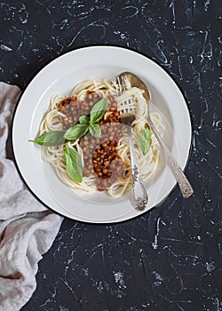 Spaghetti with vegetarian lentil bolognese on a dark background.