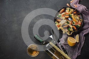 Spaghetti vongole, Italian seafood pasta with clams and mussels, in plate with herbs and glass of white wine on rustic stone