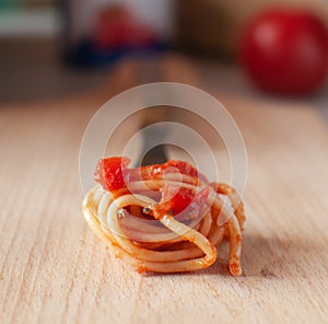 Spaghetti wound on a fork with tomatoes and basil.