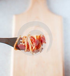 Spaghetti wound on a fork with tomatoes and basil.