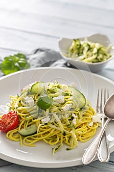 Spaghetti zucchini raw vegan pasta with feta cheese cucumber and basil