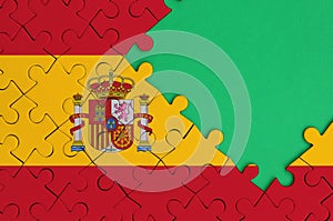 Spain flag is depicted on a completed jigsaw puzzle with free green copy space on the right side