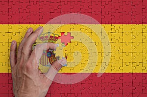 Spain flag is depicted on a puzzle, which the man`s hand completes to fold