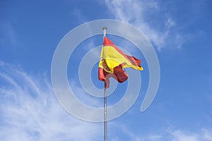 Spain flag on a mast in the wind on blue sky background