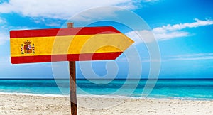 Spain flag on wooden table sign on beach background. It is summer sign of Spain