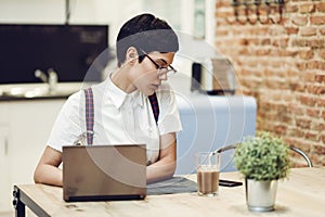 Spain, Madrid, Madrid. Young woman with very short haircut typing with a laptop at home. Working at home concept.