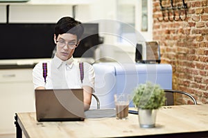 Spain, Madrid, Madrid. Young woman with very short haircut typing with a laptop at home. Working at home concept.