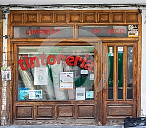 Spain; Sept 2020: Exterior of a dry cleaning store. Old wooden door and windows. Traditional shop with red letters on the glass.