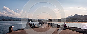 Spain; Sept 2020: People walking at the pier by the sea. Promenade in front of a traditional fishing village at sunset time.