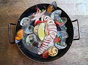 Spainish international cuisine orthodox with fried squid, clams, octopus, lemon and mussel in black pan