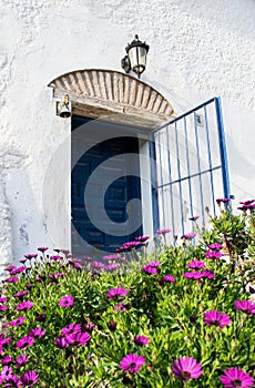 Spanish blue old entrance door with the open gate in white house