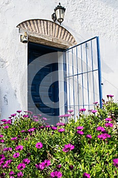 Spanish blue old entrance door with the open gate in white house