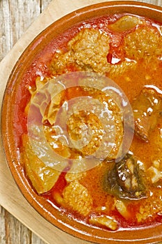 Spanish callos in an earthenware dish on a wooden table