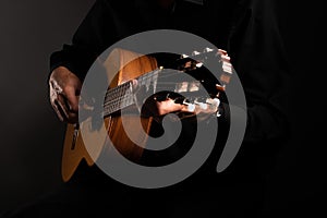 Spanish classical guitar and guitarist`s hands up close on a black background with copy space