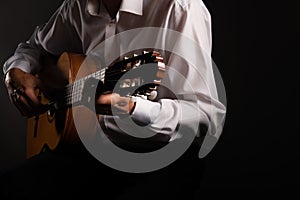 Spanish classical guitar and guitarist`s hands up close on a black background with copy space