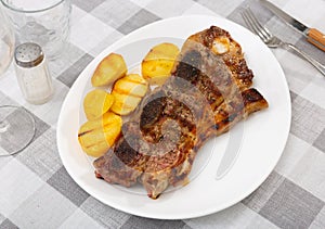 Spanish cuisine churrasco de ternera, spare ribs with potatoes on ceramic plate