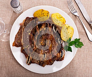 Spanish cuisine churrasco de ternera, spare ribs with potatoes on ceramic plate