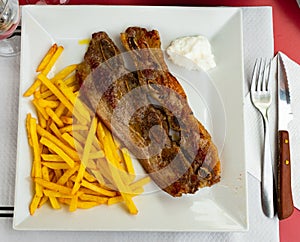 Spanish cuisine churrasco de ternera, spare ribs with potatoes on white ceramic plate
