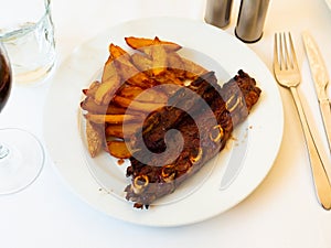 Spanish cuisine churrasco de ternera, spare ribs with potatoes on white ceramic plate