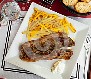 Spanish cuisine churrasco de ternera, spare ribs with potatoes on white ceramic plate photo