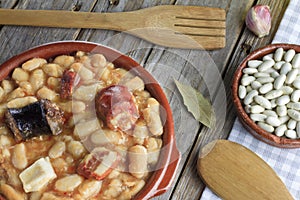 Spanish fabada in an earthenware dish and a wooden fork and knife