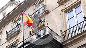 Spanish flag waving by the wind at the entrance of top of governmental building in Madrid