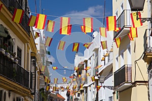 Spanish flags on the street in Seville, Spain. Details of old buildings facade, wall with wooden frame windows.