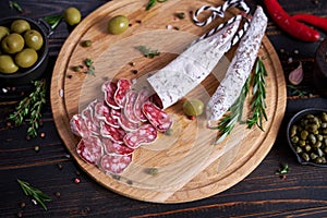 Spanish fuet salami sausageon wooden cutting board at domestic kitchen