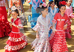 Spanish girls in traditional dress walking alongside Casitas at the Seville Fair.