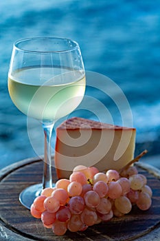 Spanish goat milk cheese with paprika coating and ripe pink table grapes served with white wine on outdoor terrace