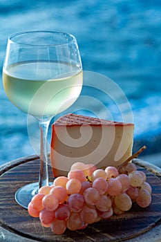 Spanish goat milk cheese with paprika coating and ripe pink table grapes served with white wine on outdoor terrace