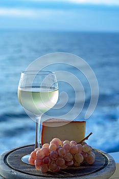 Spanish goat milk cheese with paprika coating and ripe pink table grapes served with white wine on outdoor terrace