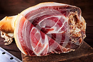 Spanish ham, bellota, jamon serrano, crudo, italian prosciutto, whole leg,  parma ham cut with a knife and lying on a wooden board photo