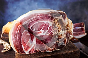 Spanish ham, bellota, jamon serrano, crudo, italian prosciutto, whole leg,  parma ham cut with a knife and lying on a wooden board photo
