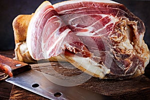 Spanish ham, bellota, jamon serrano, crudo, italian prosciutto, whole leg,  parma ham cut with a knife and lying on a wooden. Top