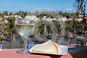 Spanish hard manchego, cow, sheep and goat cheese, cold white wine and blue swimming pool on background