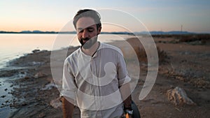 Spanish hipster man with guitar walking by the Torrevieja Pink lake at sunset, Alicante