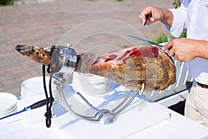 Spanish Iberian ham or Pata Negra mounted on a wooden stand with a butcher cutting slices of it