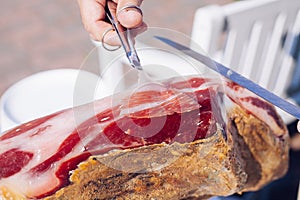 Spanish Iberian ham or Pata Negra mounted on a wooden stand with a butcher cutting slices of it