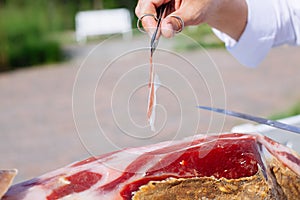 Spanish Iberian ham or Pata Negra mounted on a wooden stand with a butcher cutting slices of it