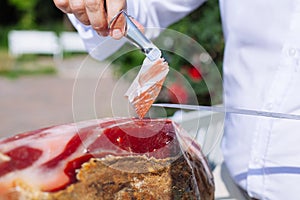 Spanish Iberian ham or Pata Negra mounted on a wooden stand with a butcher cutting slices of it